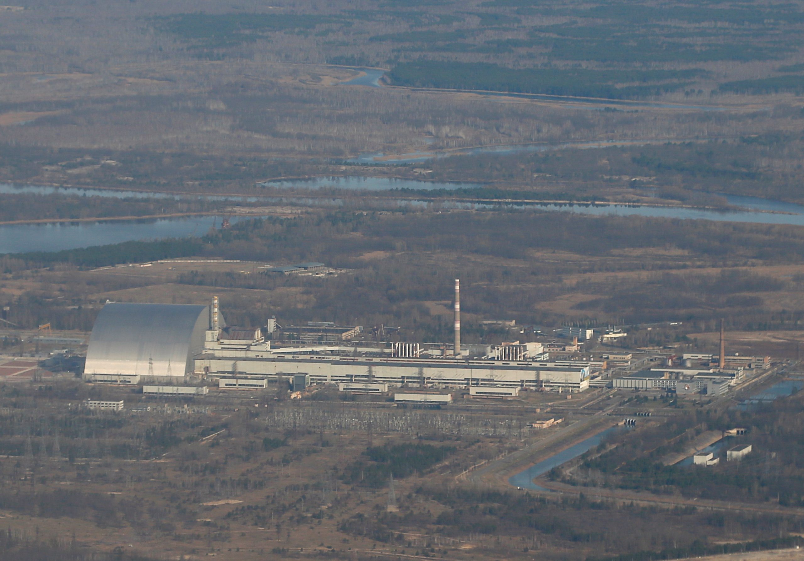 An aerial view from an aircraft shows a new Safe Confinement (NSC) structure above the old sarcophagus covering the damaged 4th reactor at the Chernobyl Nuclear Power Plant during a tour of the Chernobyl Exclusion Zone, Ukraine, April 3, 2021. REUTERS/Gleb Garanich/File Photo