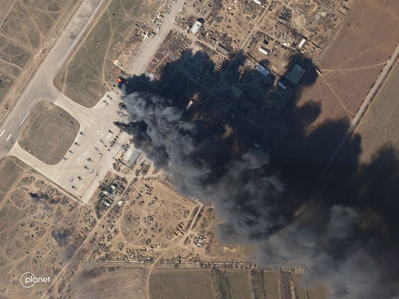 A satellite image shows a plume of smoke rising from Kherson International Airport on Tuesday, March 15.  When zoomed in, the images show a number of helicopters in flames.