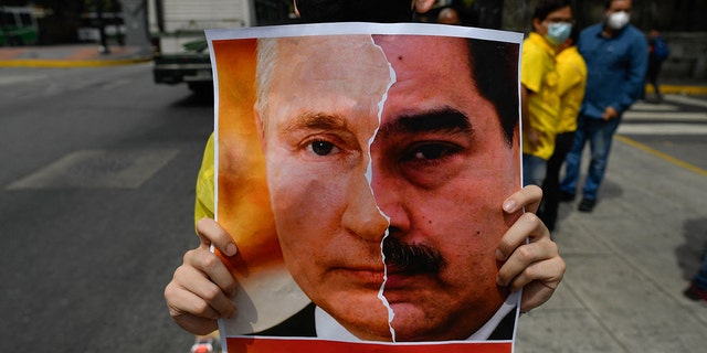 Primero Justicia holds a sign showing the face of Russian President Vladimir Putin and Venezuelan President Nicolas Maduro 