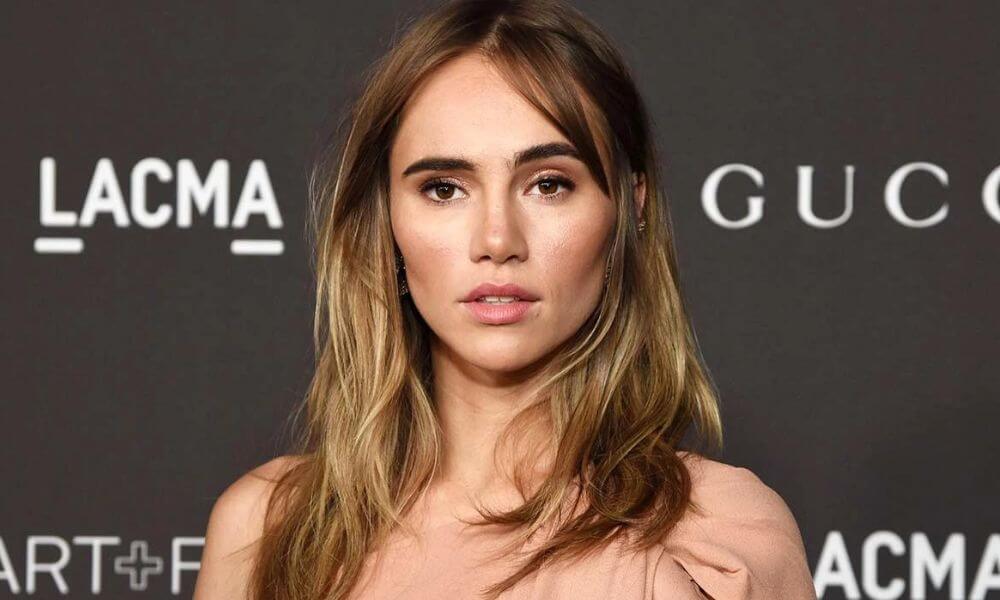 Suki Waterhouse Shows Off Her Toned Abs In A White Crop Top And Purple Metallic Jeans